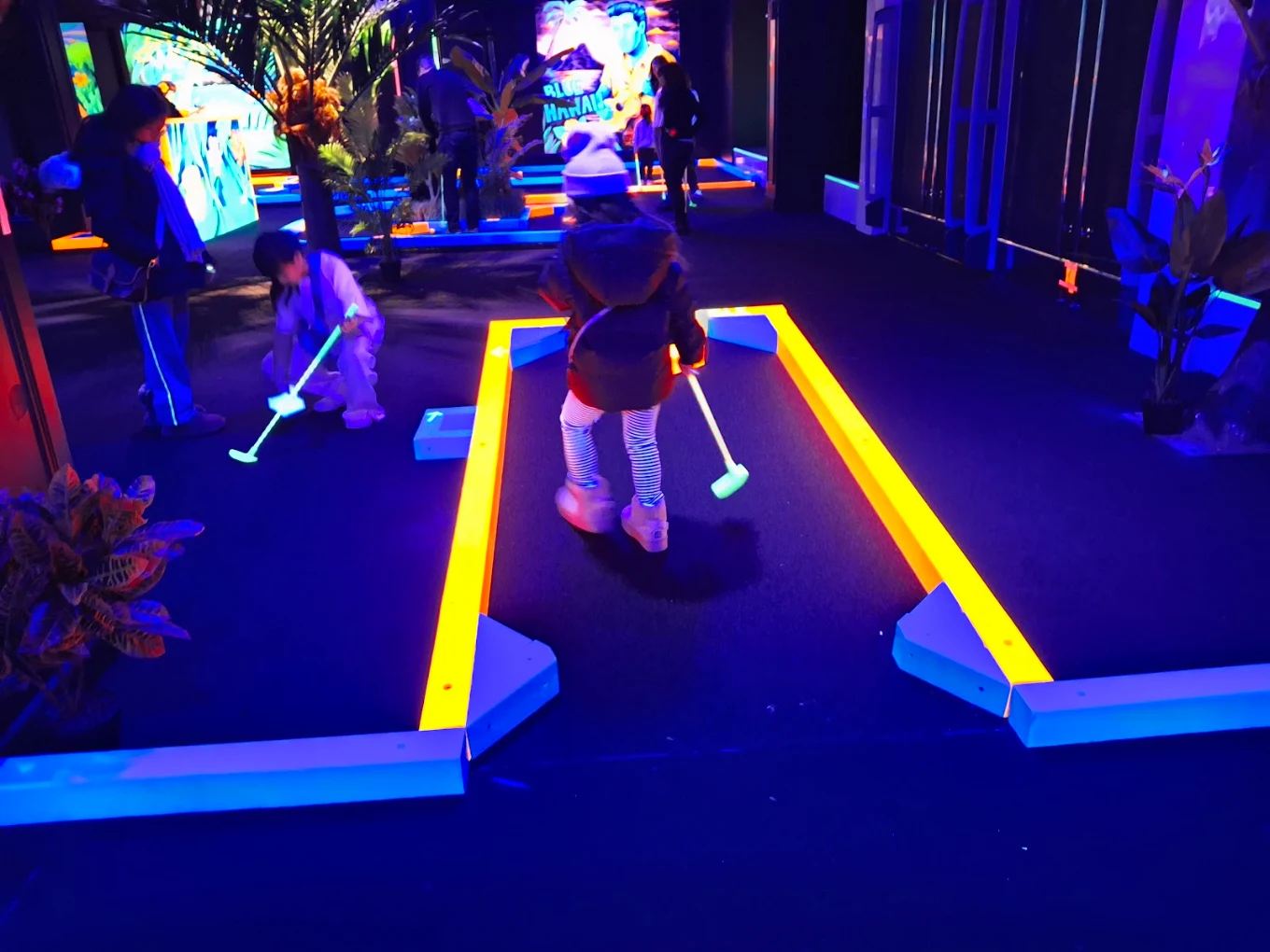 Kids putting on a neon glow-in-the-dark mini golf course
