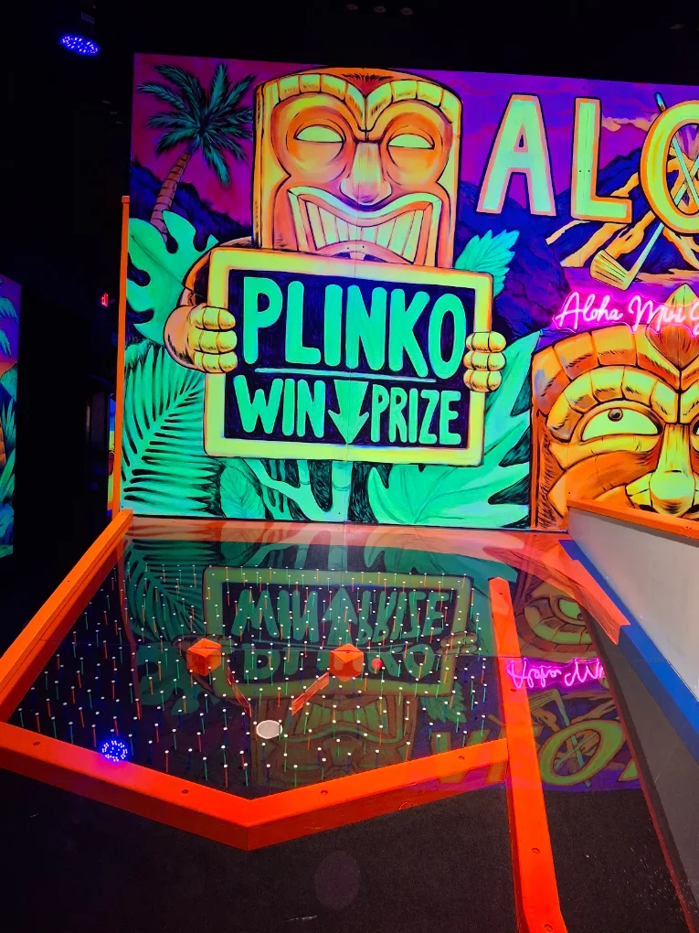 Neon tiki Plinko prize game glowing under blacklight