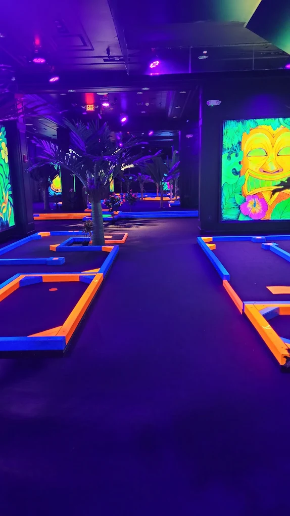 Rows of glowing mini golf holes framed by tropical palms and tiki murals
