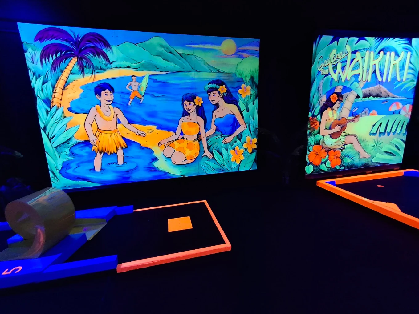Waikiki beach hula mural beside a glowing mini golf hole